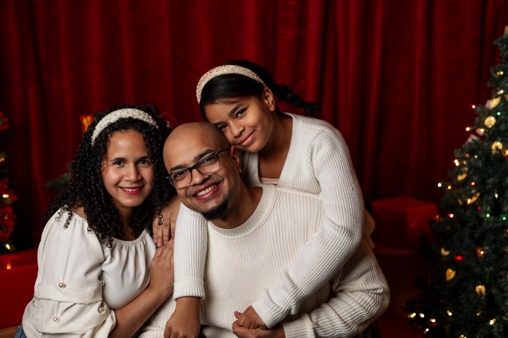 Family in cream knitwear by the Christmas tree at night