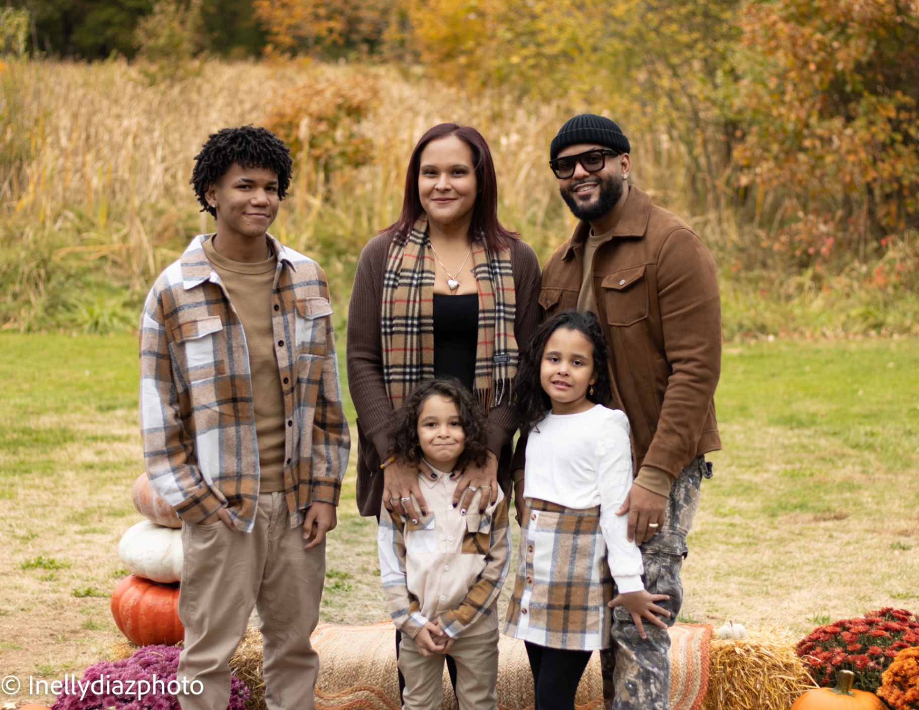 Family in earth-toned plaid among amber autumn fields